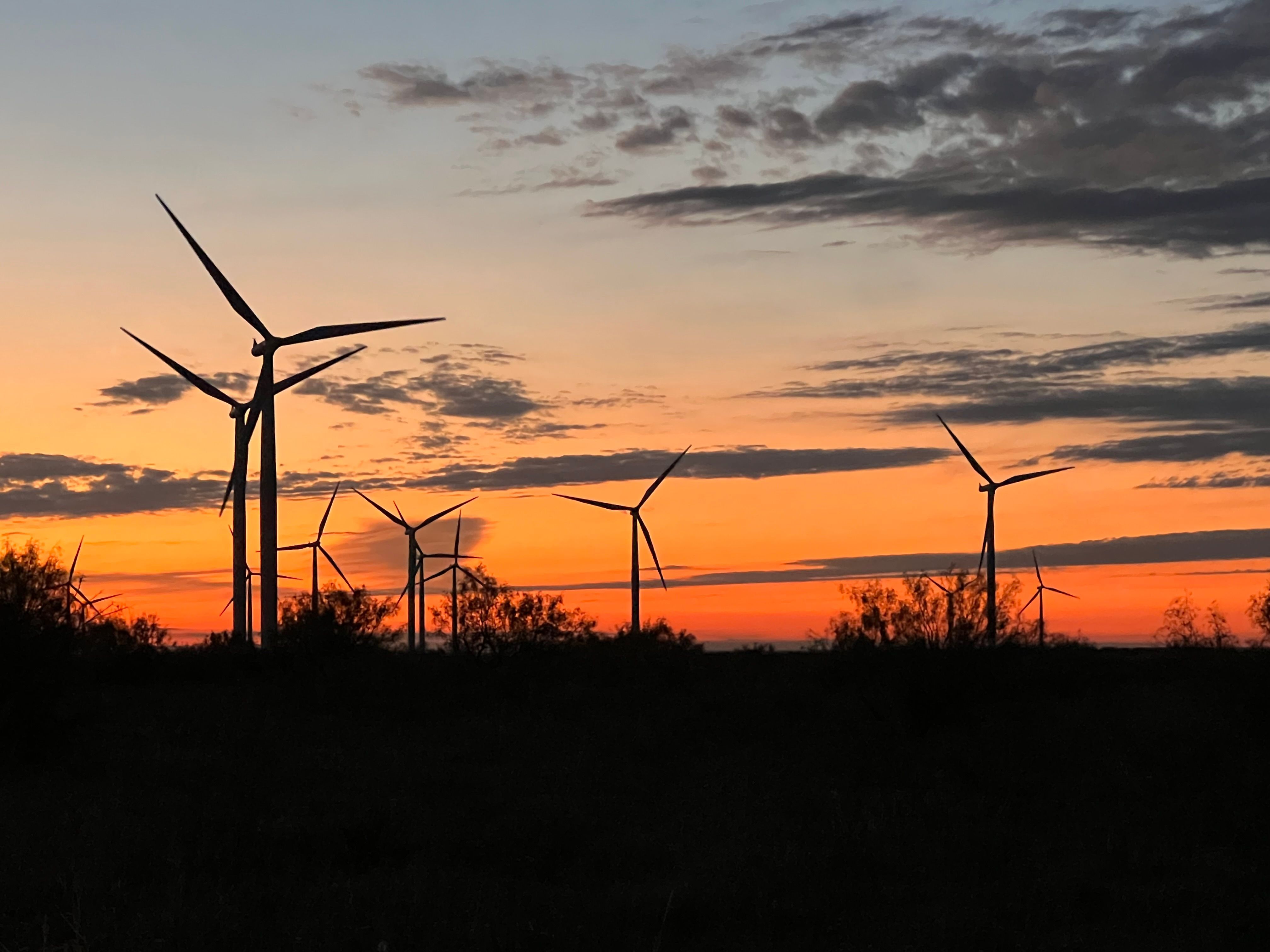 Wind turbines at Hackberry Wind Farm in Shackleford County, Texas, silhouetted against a sunset sky, part of Dauntless Energy’s refurbishment project.